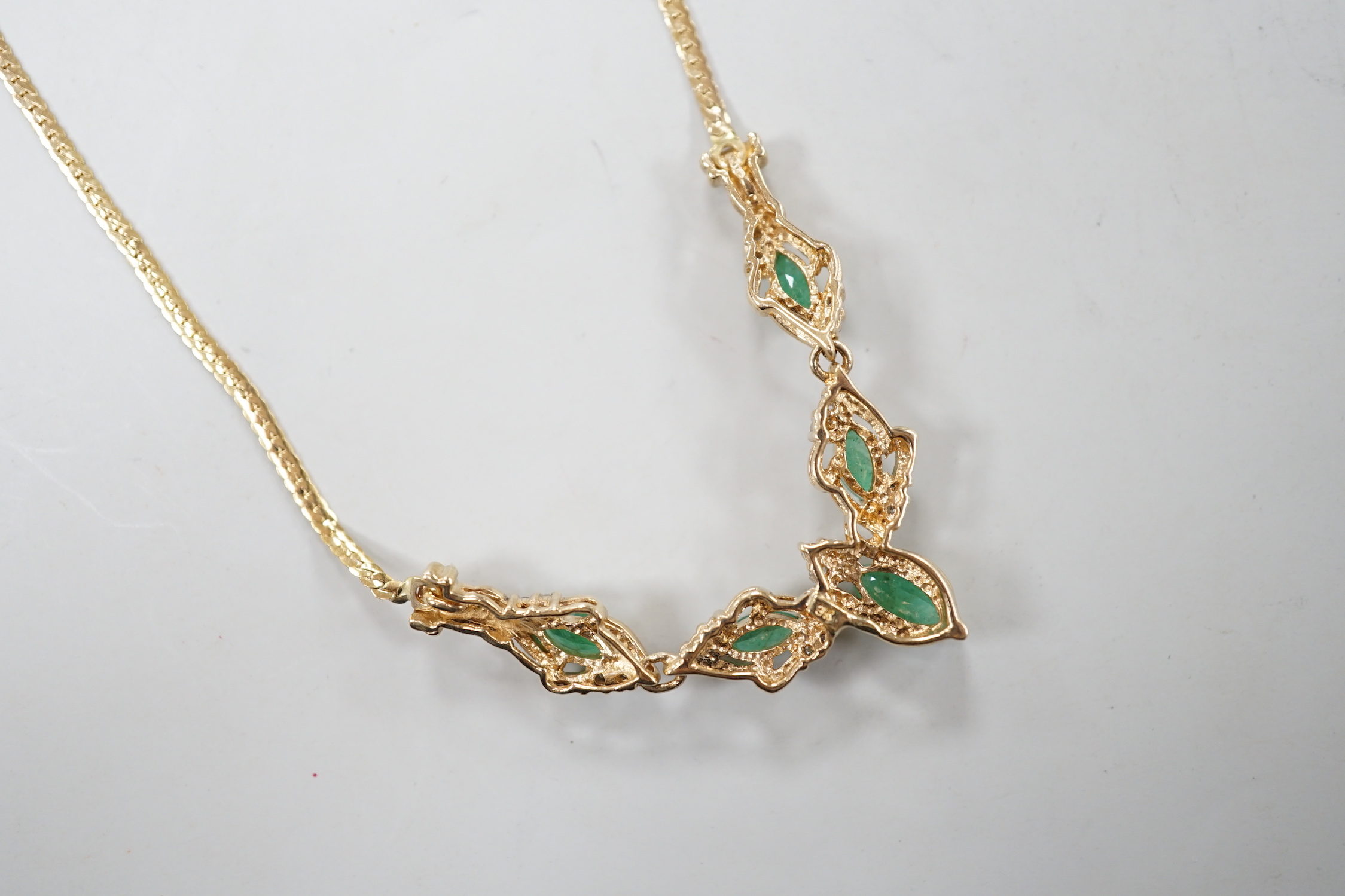 A modern 9ct gold, five stone marquise cut emerald and diamond chip cluster set necklace, 46cm, gross weight 6.2 grams.